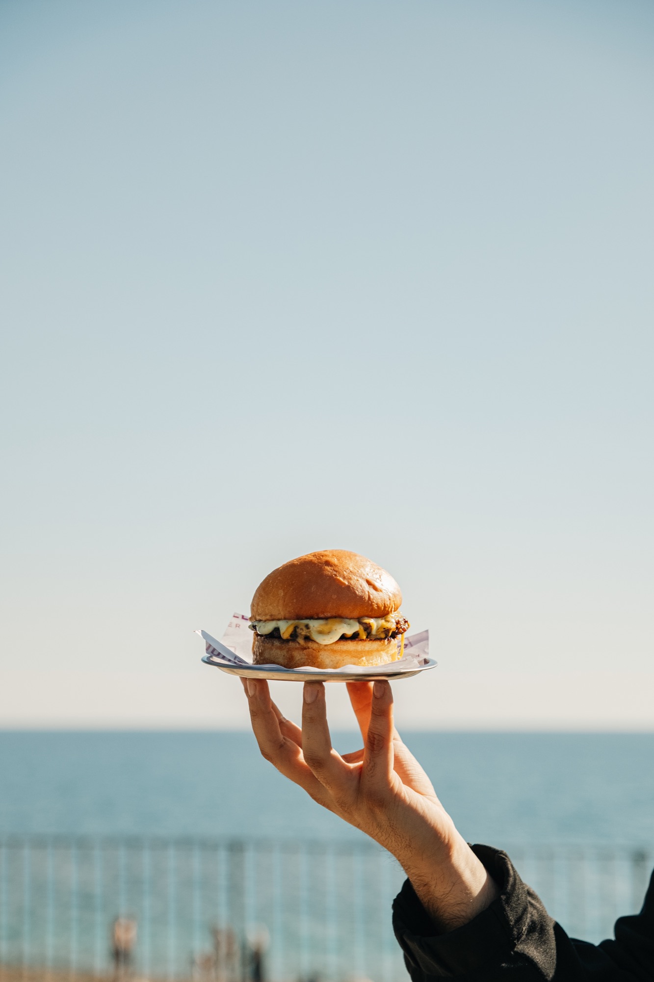 Deniz manzarası önünde elde tutulan Mahalle Burger