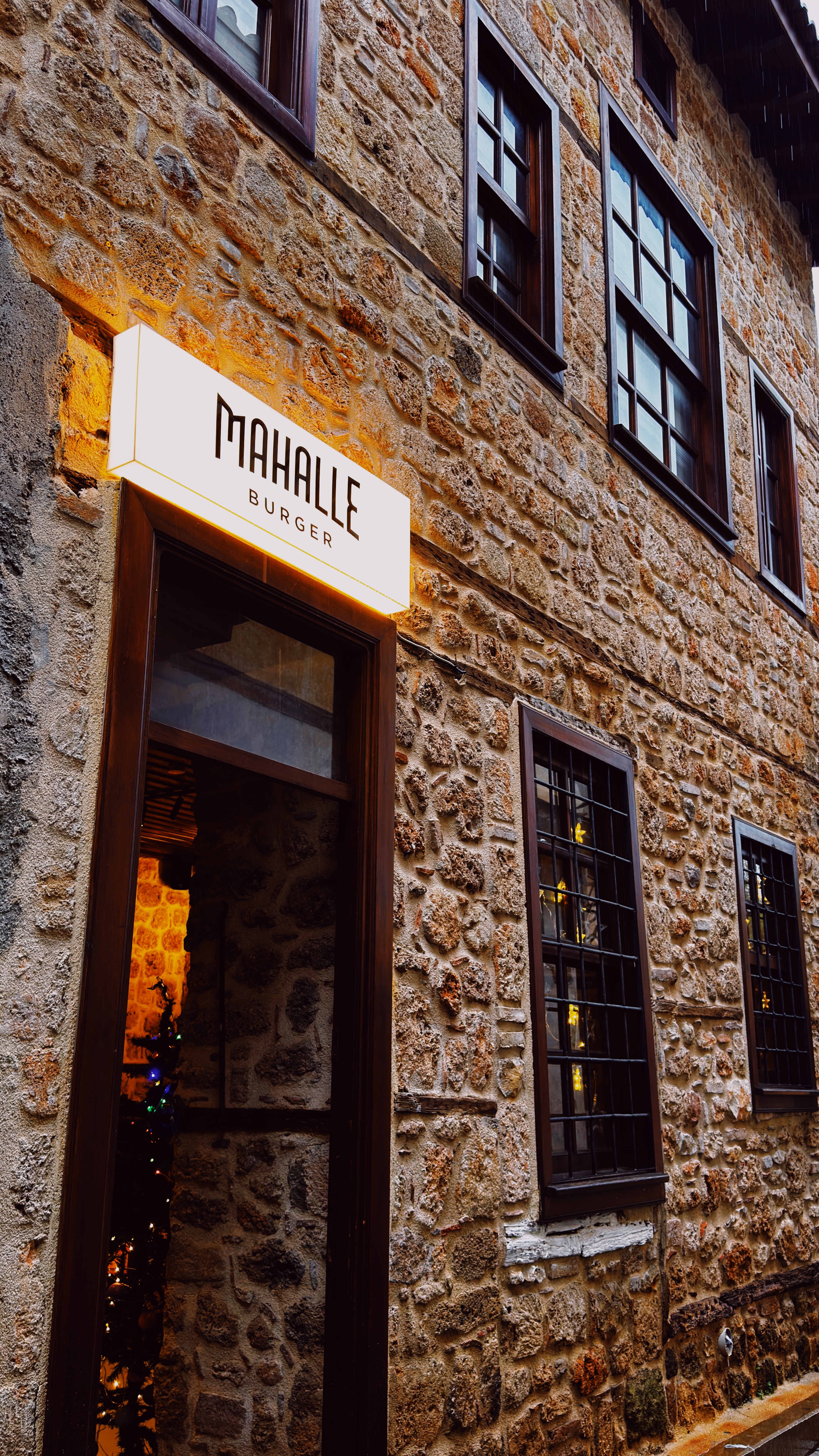 Stone exterior and illuminated Mahalle Burger sign at the Kaleiçi branch