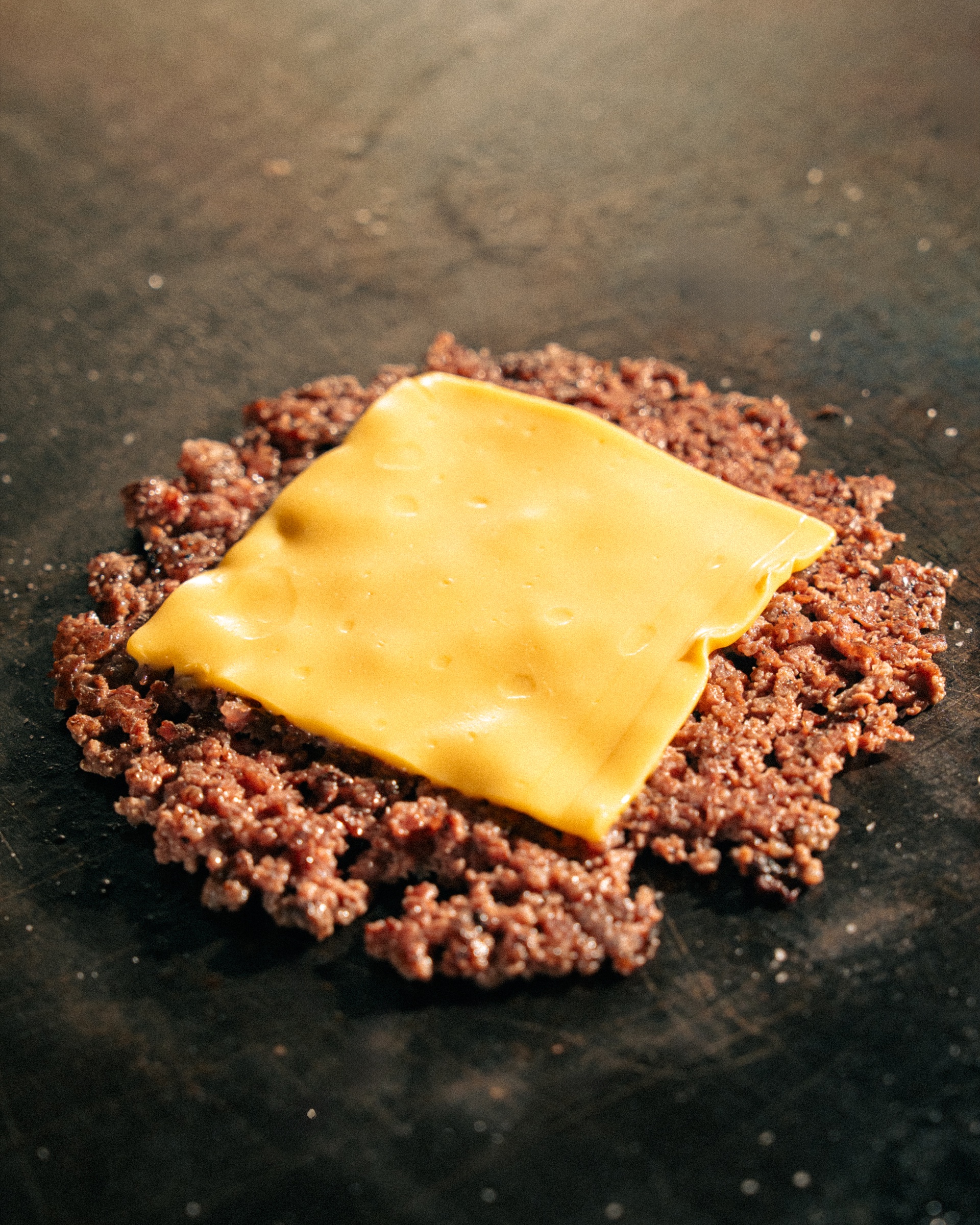 Melted cheese on a freshly smashed beef patty